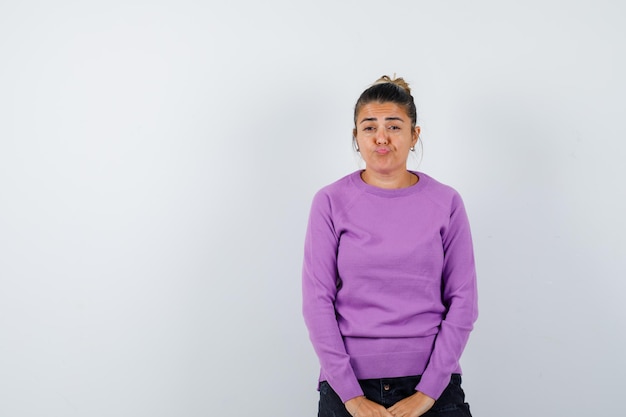 Lady looking at camera, curving lips, frowning face in wool blouse and looking pensive 