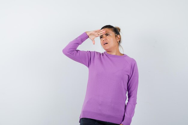 Lady looking far away with hand over head in wool blouse and looking focused 