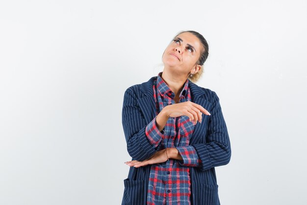 Lady looking up in shirt, jacket and looking pensive , front view.