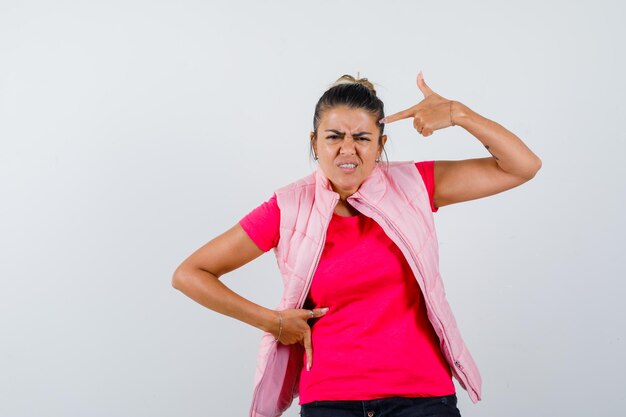 Lady making suicide gesture in t-shirt, vest and looking spiteful