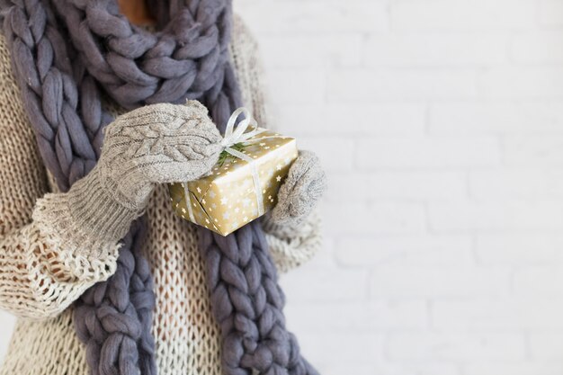 Lady in mitts and scarf with gift box in hands