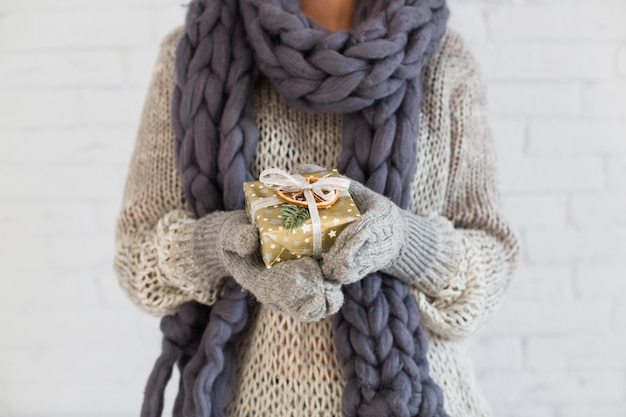 Lady in mitts and scarf with present box in hands