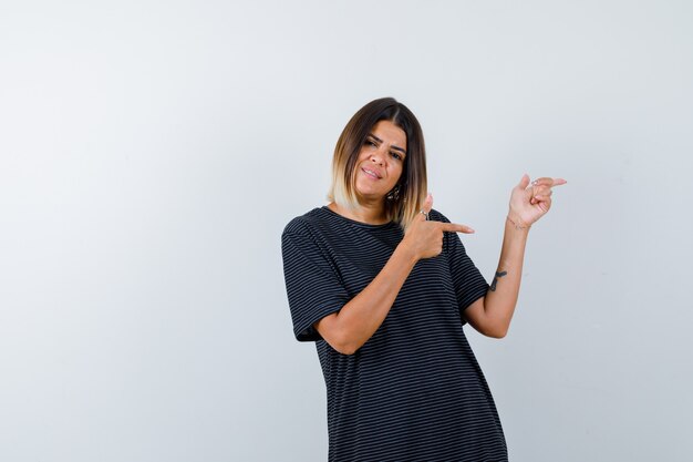 Lady pointing right in black t-shirt and looking optimistic , front view.