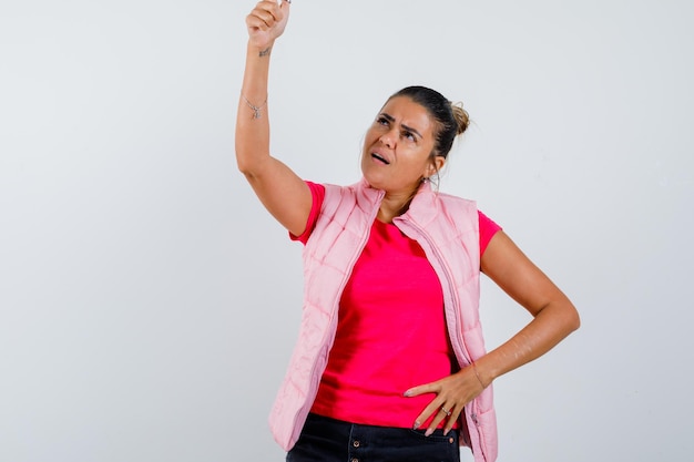 Signora che indica in t-shirt, gilet e sembra esitante