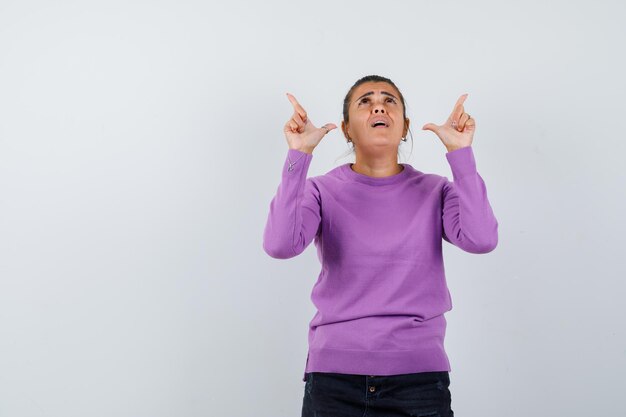 Lady pointing up in wool blouse and looking grateful 