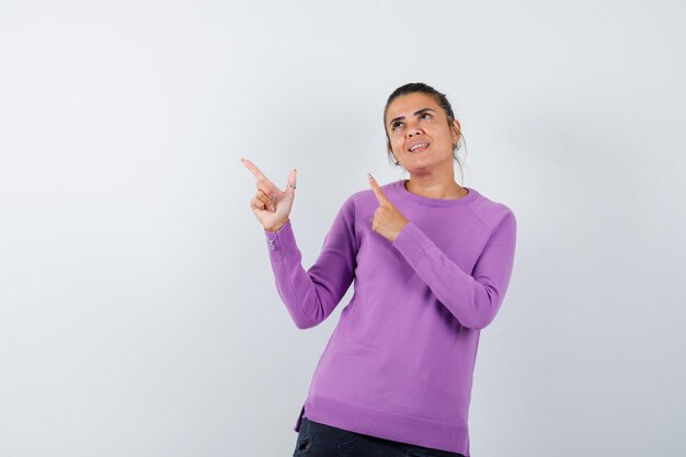 Lady pointing up in wool blouse and looking merry 