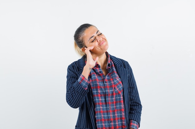 Lady pretending to listen to music in shirt, jacket and looking delighted , front view.