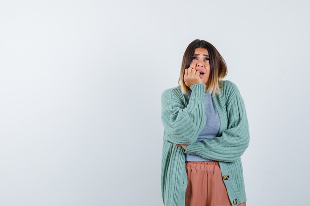 Lady propping chin on hand in casual clothes and looking anxious. front view.