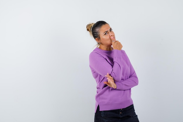 Lady propping chin on hand in wool blouse and looking pensive 