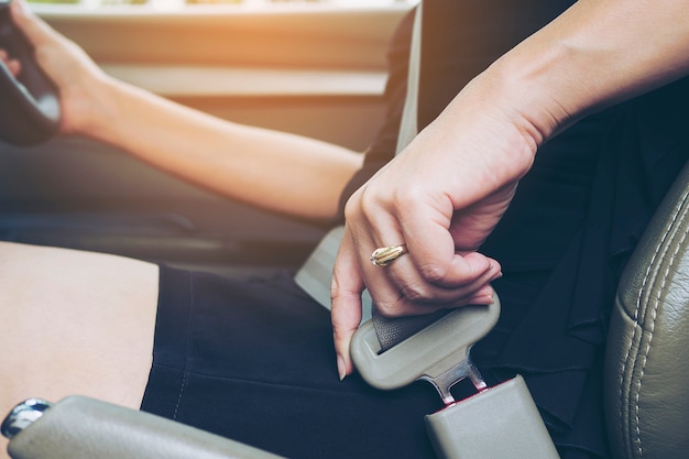 Lady putting car seat belt before driving, close up at belt buckle, safe drive concept
