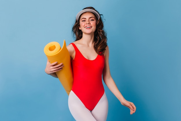 Lady in red bodysuit and white leggings looking at front with smile