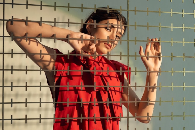 Lady in red posing behind grate