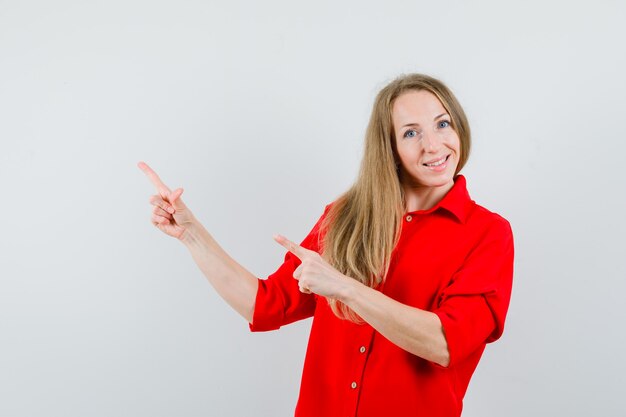 Lady in red shirt pointing at upper left corner and looking glad ,