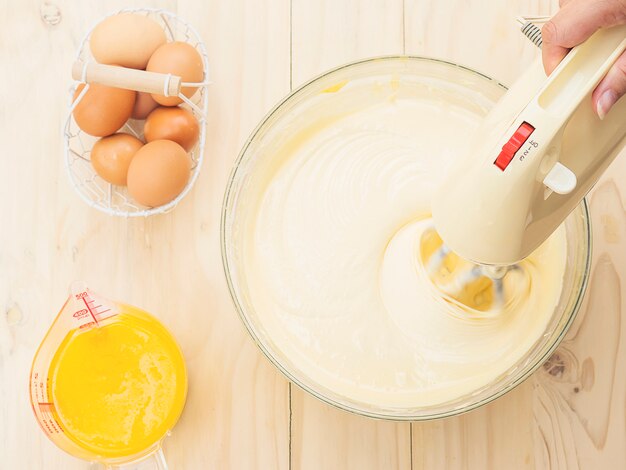 계란과 버터와 손 혼합 기계를 사용하여 케이크를 준비하는 레이디의 손
