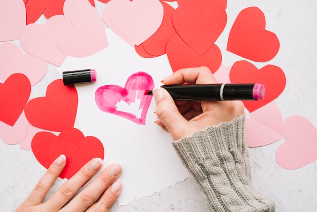 Lady's hand with marker painting heart near paper post cards