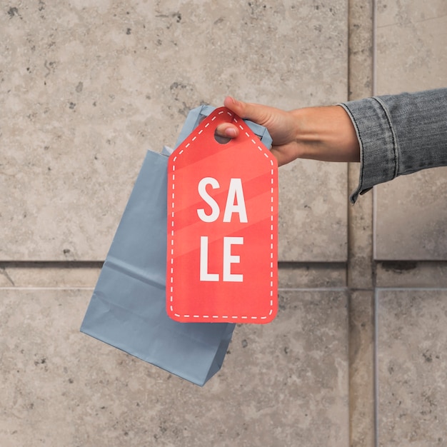 Free photo lady's hand with shopping packet and sale tablet