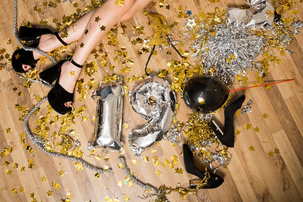 Lady's legs in evening shoes on floor between balloons numbers and tinsel