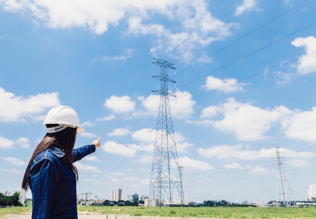 Free photo lady in safety helmet pointing at high voltage line