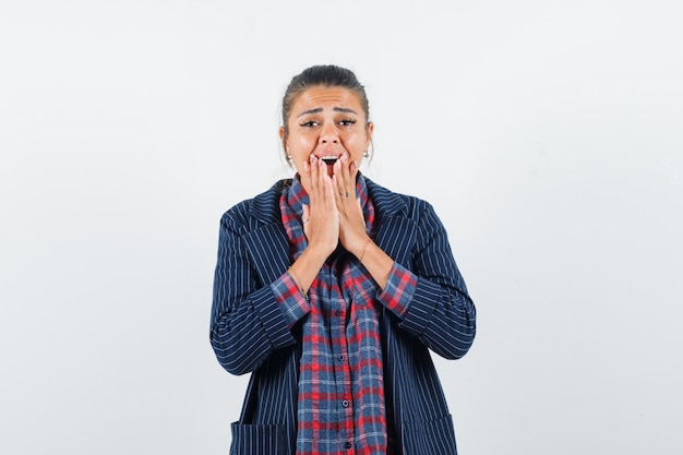 Lady in shirt, jacket holding hands on mouth and looking troubled, front view.