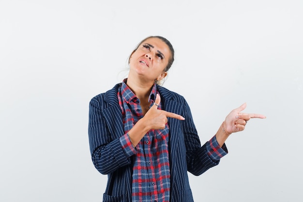 Lady in shirt, jacket pointing to the right side and looking pensive , front view.