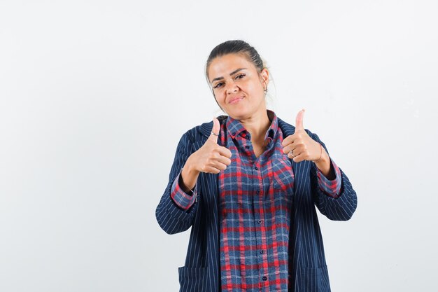 Lady in shirt, jacket showing double thumbs up and looking confident , front view.