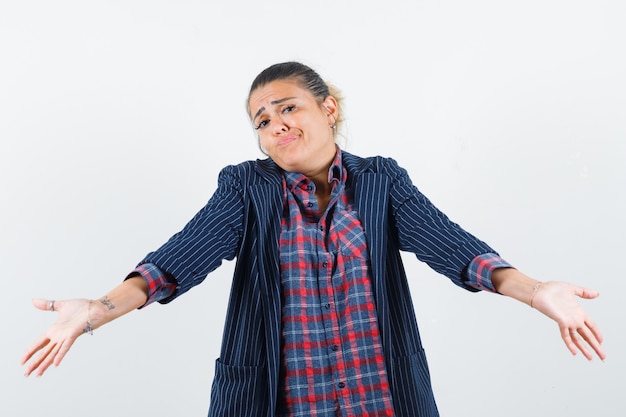 Lady in shirt, jacket showing helpless gesture and looking confused , front view.