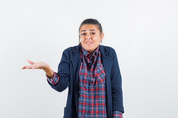 Lady in shirt, jacket showing helpless gesture and looking confused , front view.