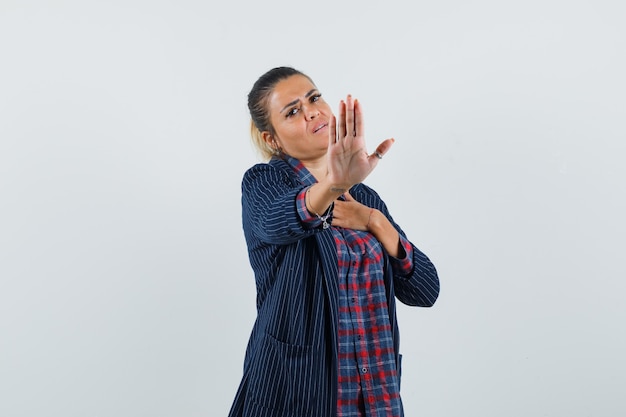 Lady in shirt, jacket showing stop gesture and looking bored , front view.