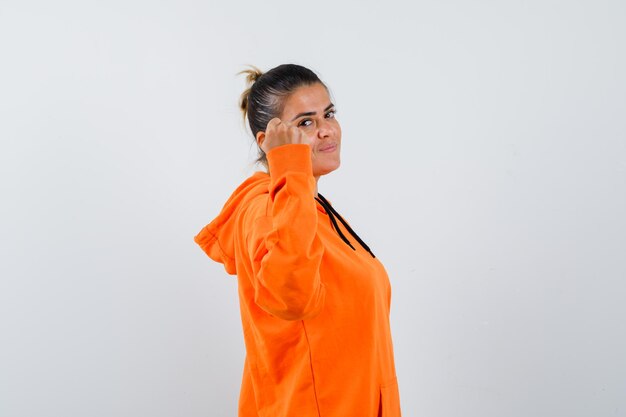 Lady showing clenched fist in orange hoodie and looking confident .
