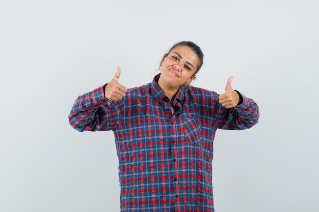 Lady showing double thumbs up in casual shirt and looking confident. front view.