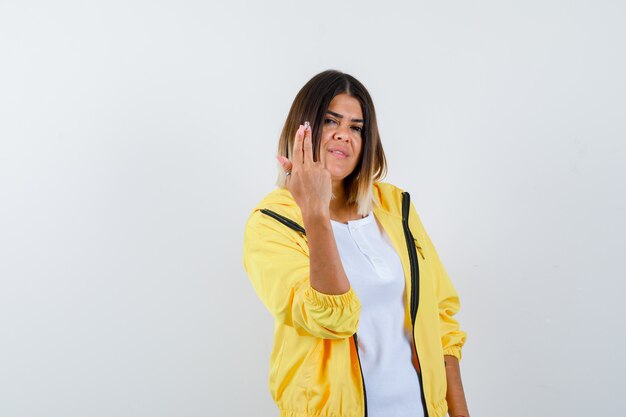 Lady showing gun gesture in t-shirt, jacket and looking proud. front view.