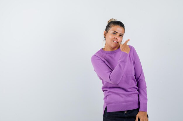 Lady showing gun gesture in wool blouse and looking cheery 