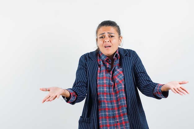 Lady showing helpless gesture in shirt, jacket and looking confused. front view.