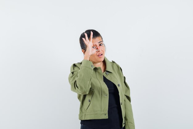 Lady showing ok sign on eye in jacket