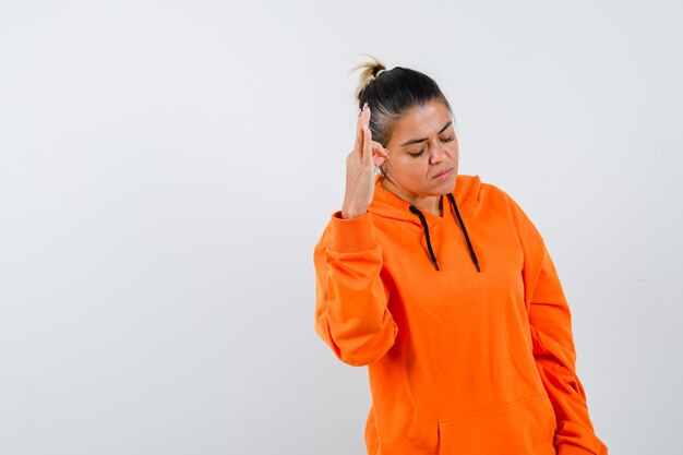 Lady showing ok sign in orange hoodie and looking confident