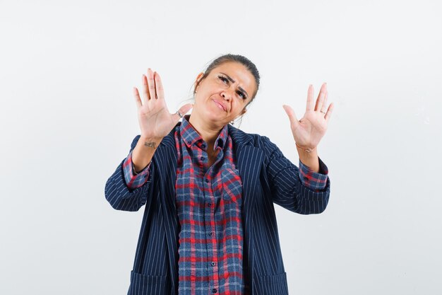 Lady showing refusal gesture in shirt, jacket and looking pensive , front view.