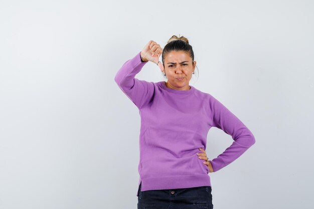 Lady showing thumb down in wool blouse and looking displeased 