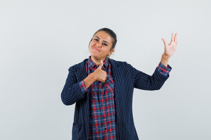 मुफ़्त फोटो lady showing thumb up, raising hand in shirt, jacket and looking confident. front view.
