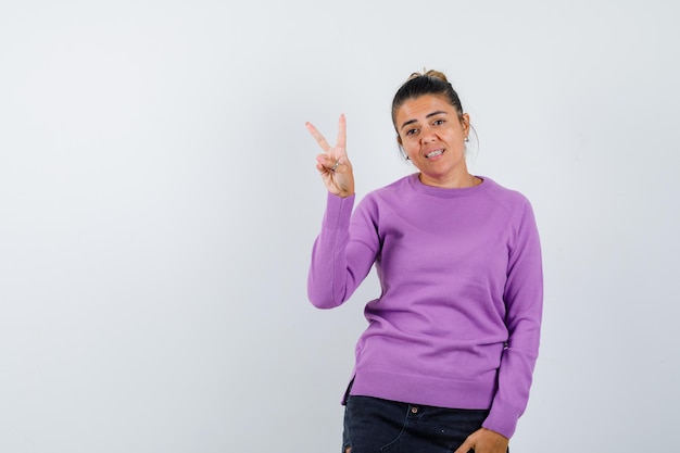 Lady showing V-sign in wool blouse and looking confident 