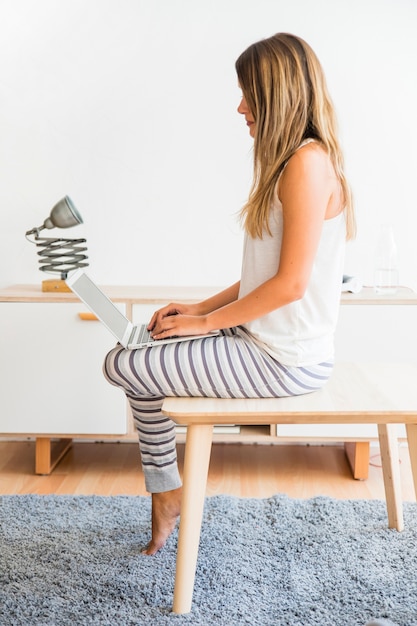 Lady sitting with laptop on legs at home 