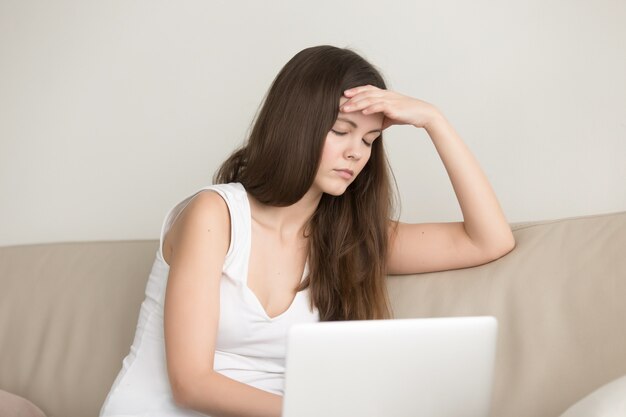 ノートパソコンでの作業後に頭痛に苦しんでいる女性