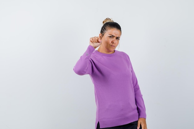 Lady threatening with fist in wool blouse and looking spiteful