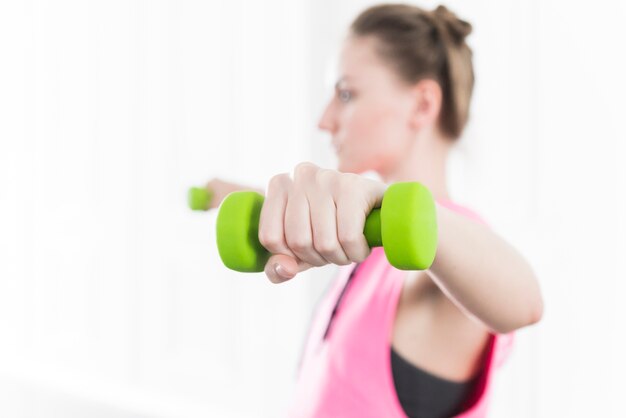 Lady training and lifting green dumbbells
