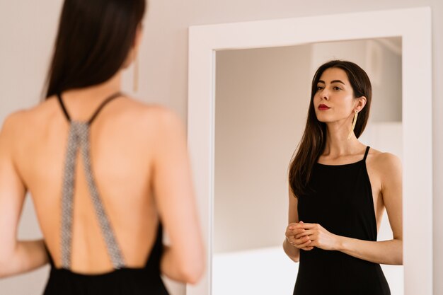 Lady wears beautiful black dress looking into the mirror