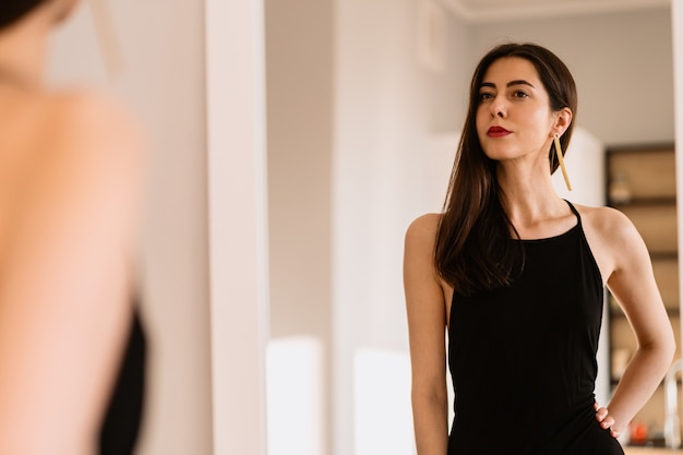 Lady wears beautiful black dress looking into the mirror