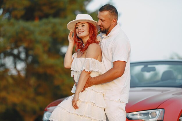 Lady in a white dress and hat. Guy in a white t-shirt. People in the forest.