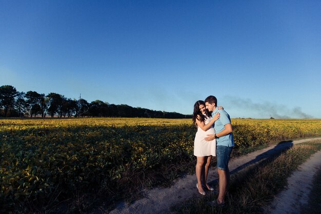 Lady in white dress hugs her man somewhere in the field 