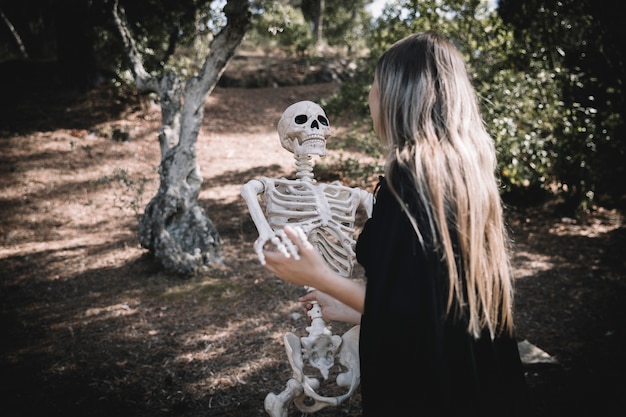 Lady in witch costume leaning skeleton