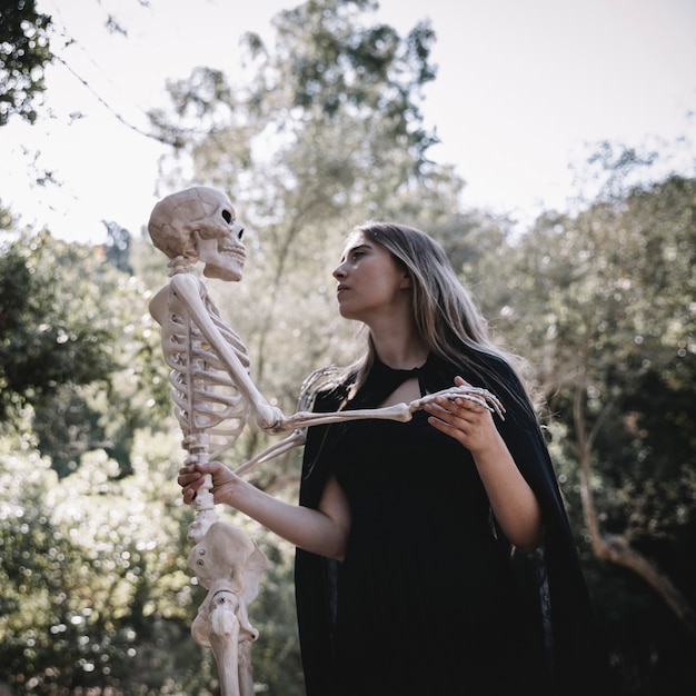 Lady in witch suit looking attentive at skeleton