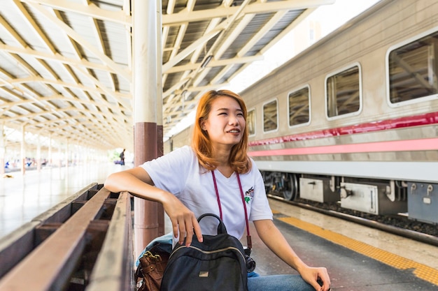 Lady with backpack and camera on bench on depot